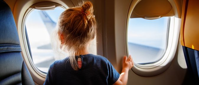 Mädchen schaut aus dem Fenster eines Flugzeuges
