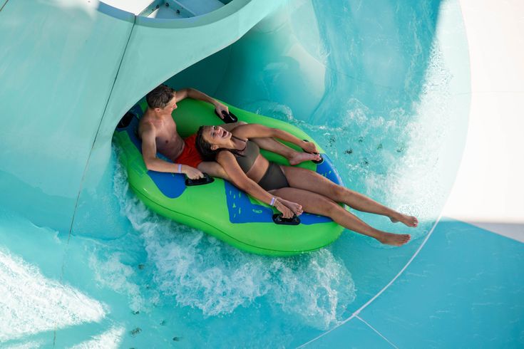 Zwei Personen auf einem Reifen von oben, sie rutschen auf einer Wasserrutsche und schauen nach oben