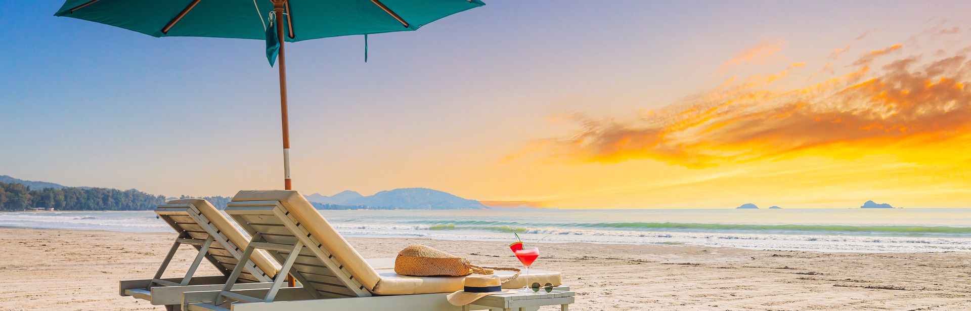 Zwei Liegen mit Sonnenschirm stehen am Strand