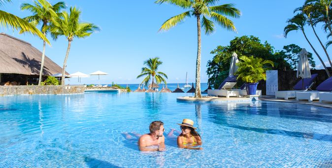 Zwei Personen liegen im Pool umgeben von Palmen