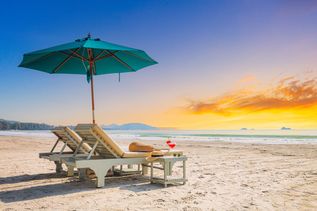 Zwei Liegen mit Sonnenschirm stehen am Strand