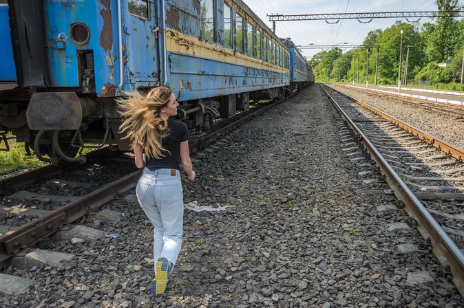 Frau läuft zu einem Zug zwischen den Gleisen