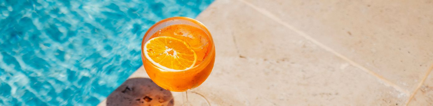Ein Oranges Getränk steht am Rand eines Pools