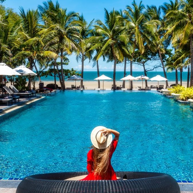 Eine Frau sitzt am Pool mit direktem Strandzugang