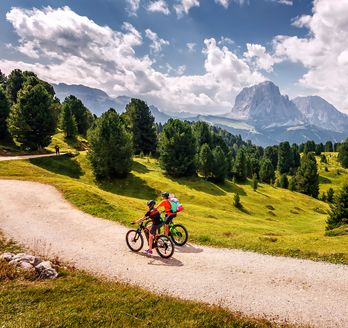 Zwei Personen fahren bei gutem Wetter Fahrrad durch eine Berglandschaft