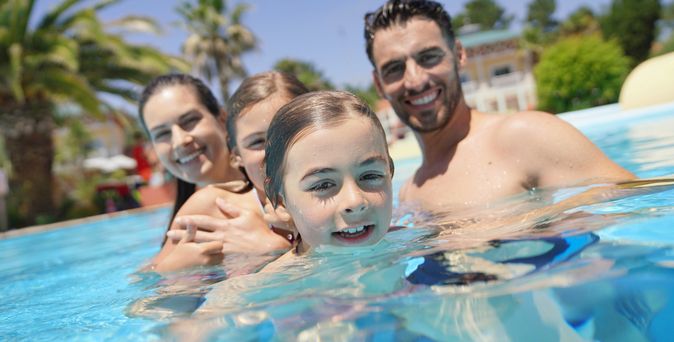 Eine Familie in einem Pool lächelt in die Kamera