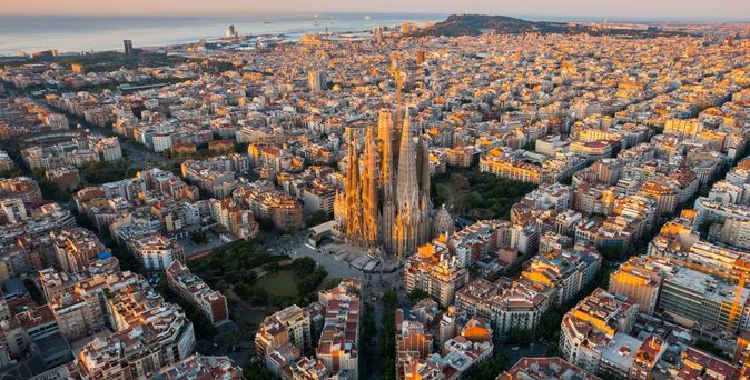 Barcelona von oben bei Sonnenuntergang, im Hintergrund das Meer