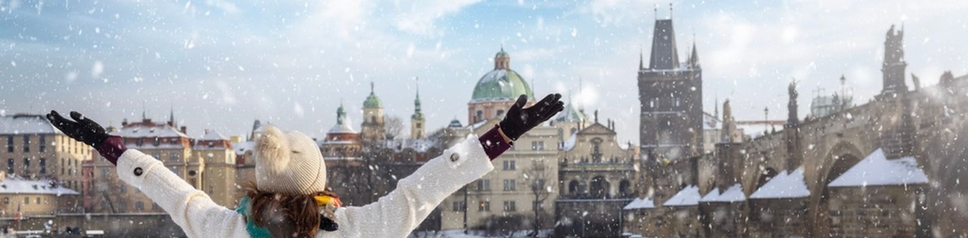 Eine Frau steht vor einem Zaun an einem Fluss, der durch eine Stadt fließt, während es schneit