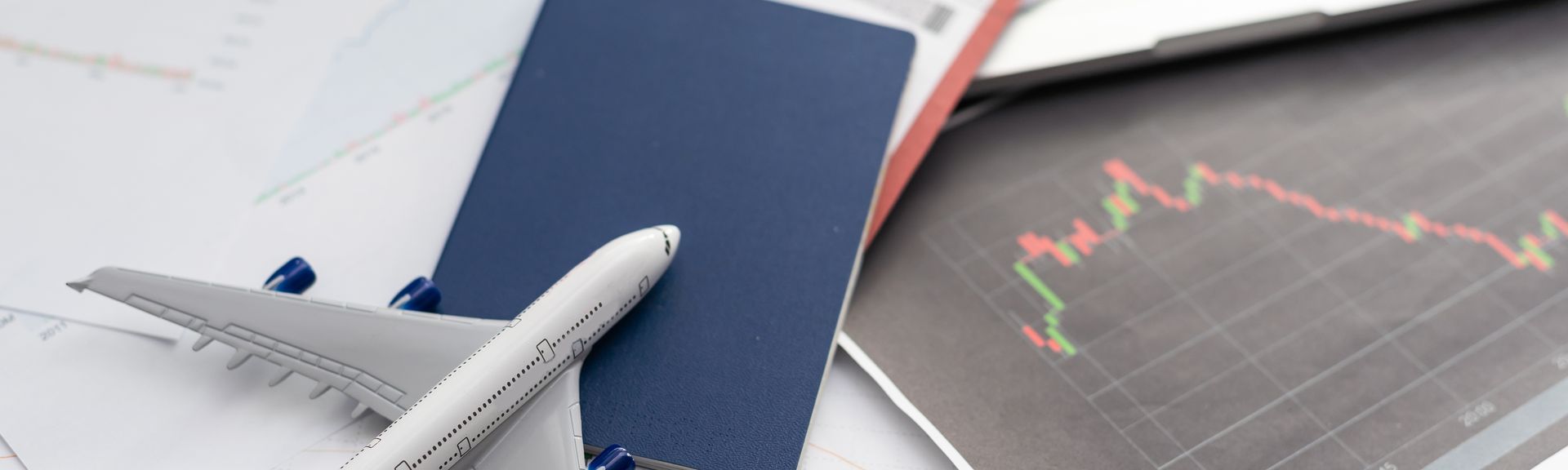 Ein Spielzeugflugzeug liegt mit einem Reisepass und einem Flugticket auf dem Tisch