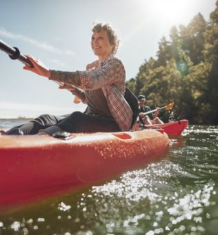 Eine Frau sitzt lächelnd in einem roten Kanu