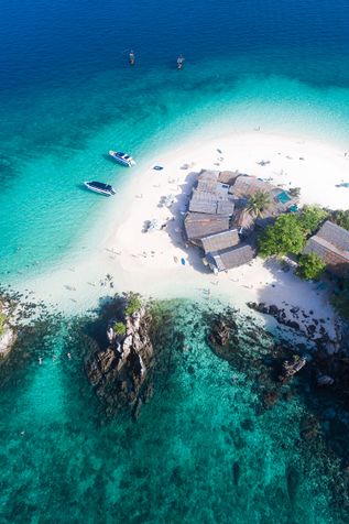 Luftaufnahme einer Insel mit Booten im türkisfarbenen Wasser 