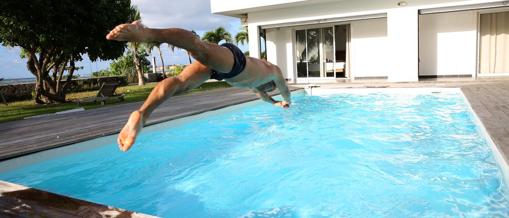 Ein Mann springt Kopfüber in einen großen privaten Pool
