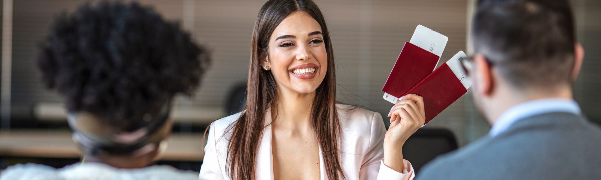 Eine lächelnde Reiseberaterin hält Ihren Kunden zwei Reisepässe mit Flugtickets hin