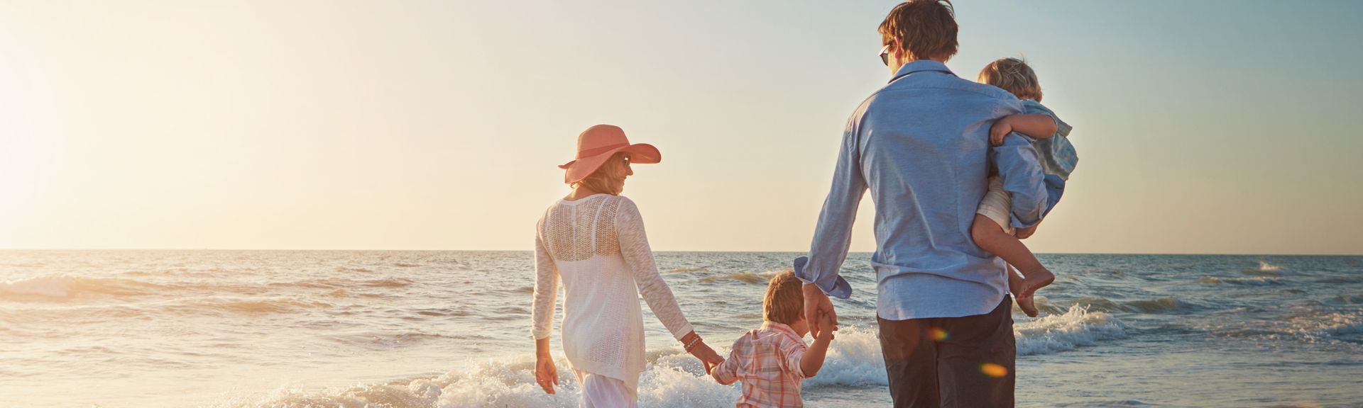Familie, die einen Strandspaziergang beim Sonnenuntergang macht