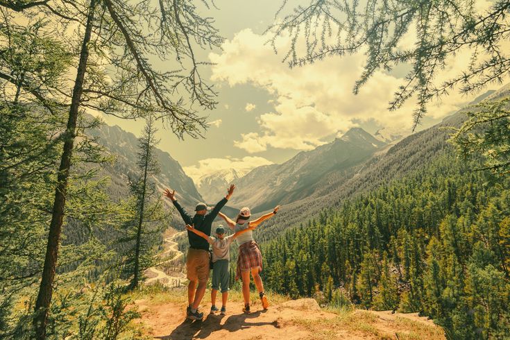 Eltern und Kind schauen beim Wandern gemeinsam auf eine Berglandschaft 