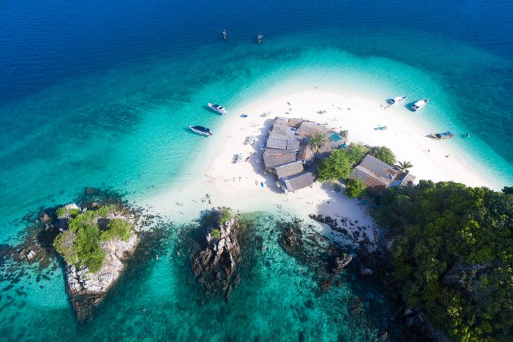 Luftaufnahme einer Insel mit Booten im türkisfarbenen Wasser 