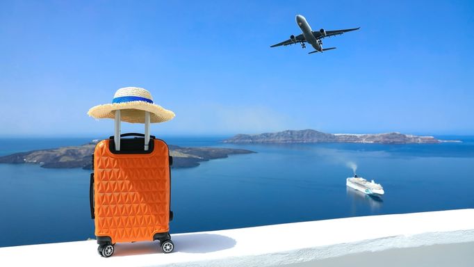 Ein Koffer steht auf einer Mauer, im Hintergrund sieht man das Meer und ein Schiff, im Himmel fliegt ein Flugzeug
