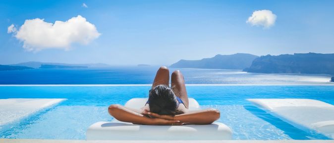Eine Frau liegt auf einer Liege im Pool mit Blick auf das Meer