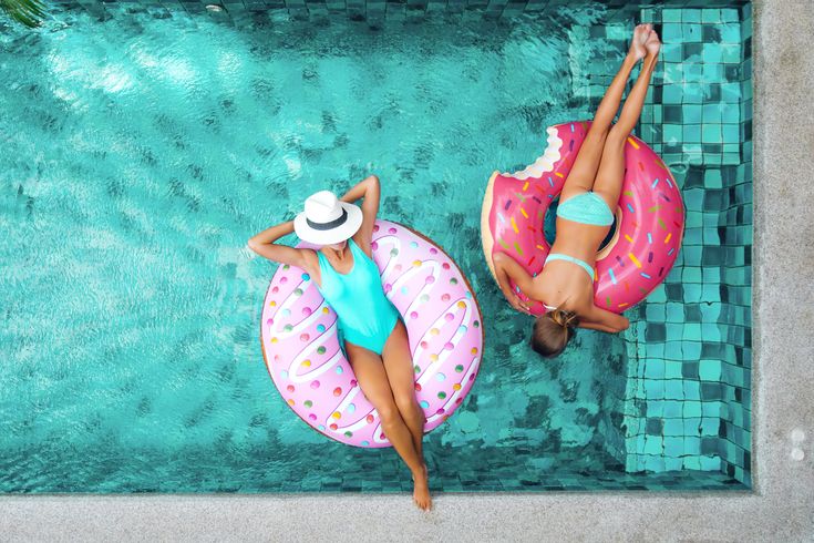 Zwei Frauen liegen in aufblasbaren Ringen in einem Pool