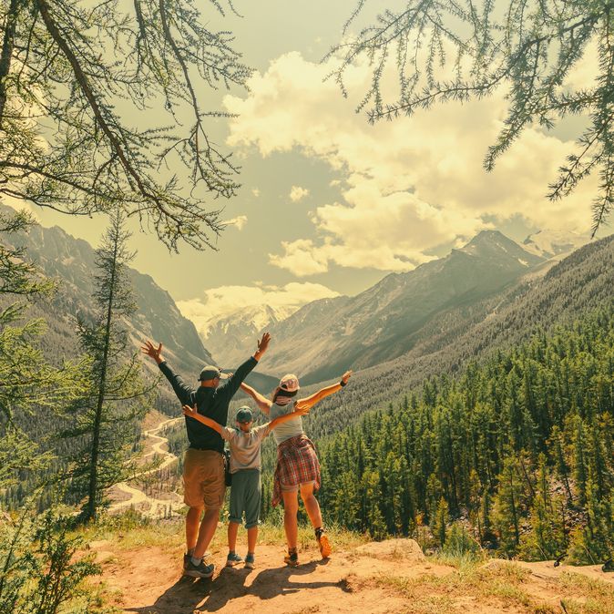 Eltern und Kind schauen beim Wandern gemeinsam auf eine Berglandschaft 